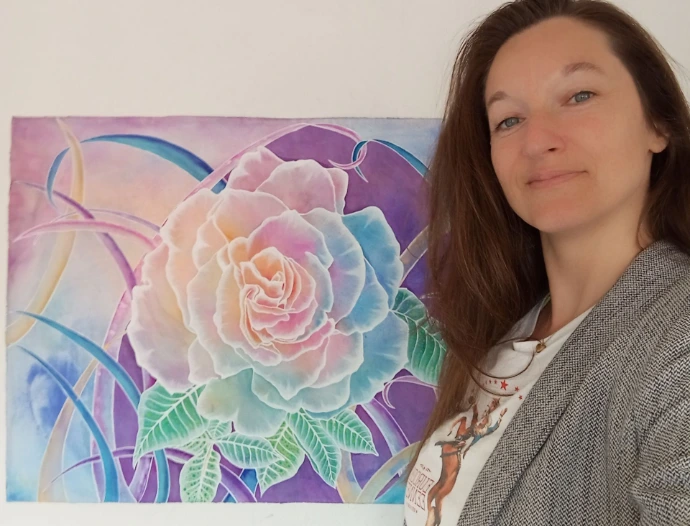 L'artiste Joanna Husson posant devant son oeuvre intitulée La Rose Arc-en-Ciel, une aquarelle multicolore